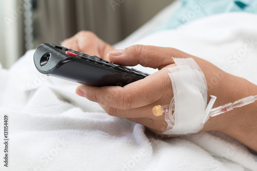 Female Patient watching TV and remote control in hand In Hospita