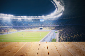 Wooden table against football stadium background