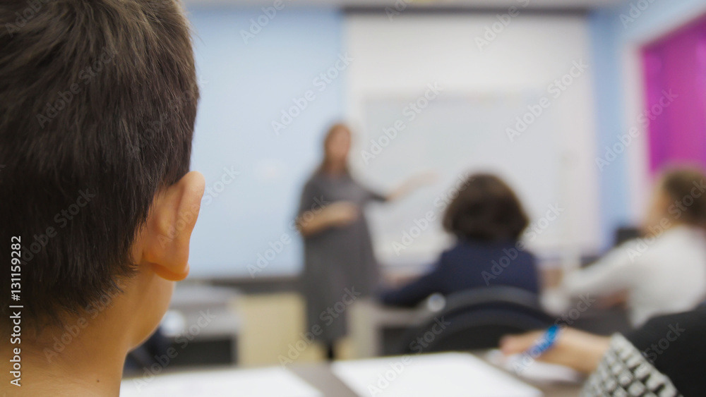 Classmates on school - children boy looking during the teacher explains the lesson Classmates on school - children boy looking during the teacher explains the lesson