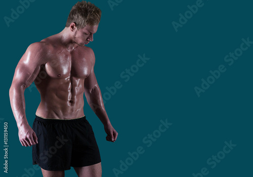 Foto Young handsome male bodybuilder with muscle and sweat body in shirts looking down
