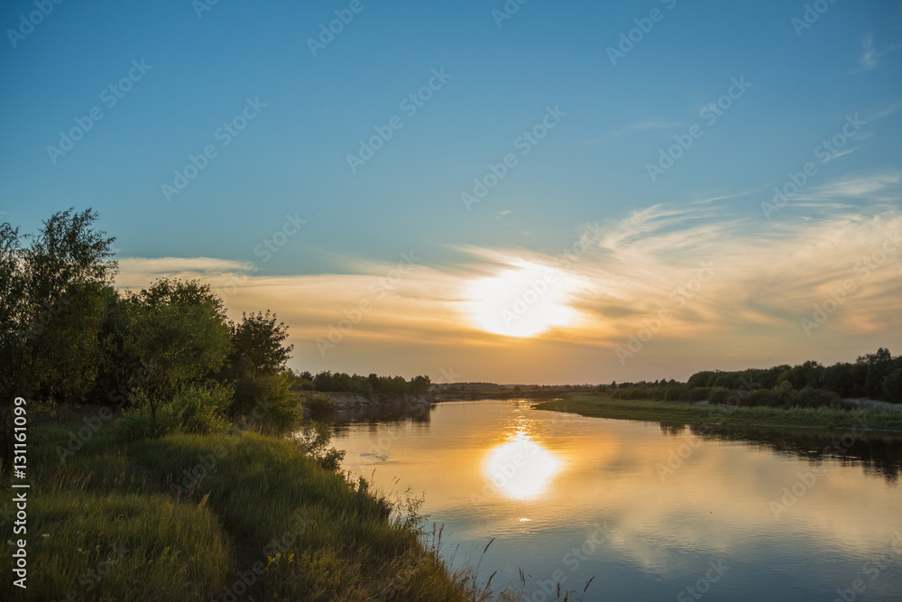 Obraz premium River at sunset time with a yellow sun and clouds