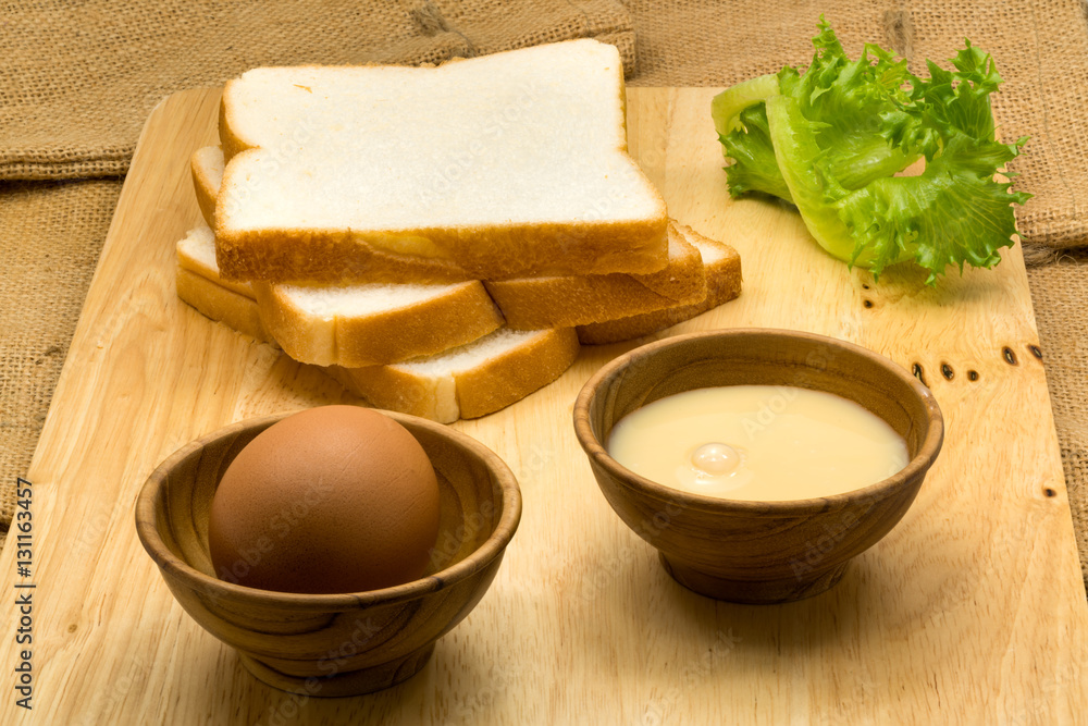 Pile of sliced breads, sweetened condensed milk and egg Pile of sliced breads, sweetened condensed milk and egg
