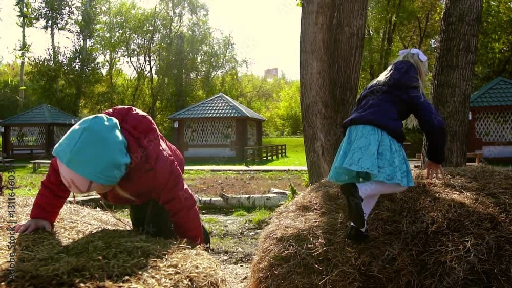 Two beautiful girls are playing in the street on a haystack Two beautiful girls are playing in the street on a haystack