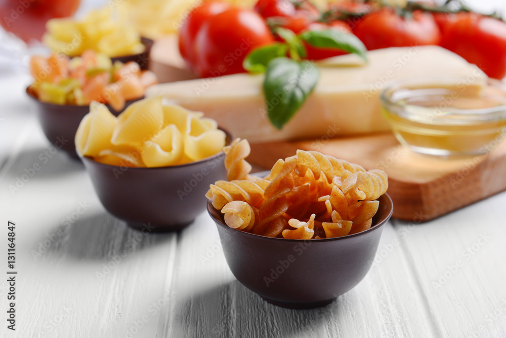 Different kinds of pasta and tomatoes on wooden background Different kinds of pasta and tomatoes on wooden background