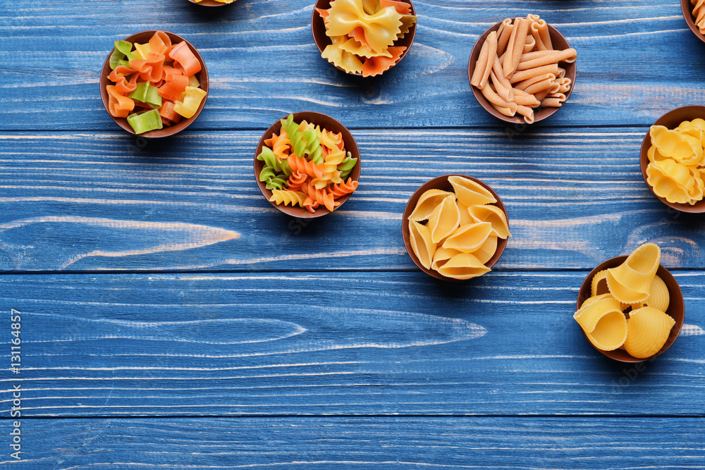 Different kinds of pasta in bowls on wooden background Different kinds of pasta in bowls on wooden background