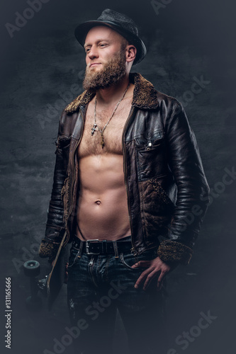 Bearded man wearing a leather jacket on naked torso.