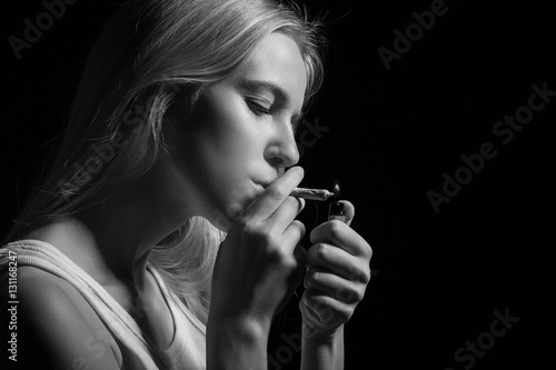 blond young woman smoking on black background, monochrome