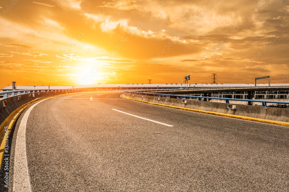 Fototapeta premium Asphalt road and woods at sunset
