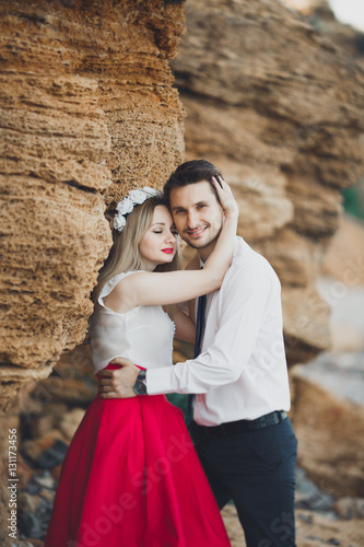 Romantic loving couple walking on the beach with rocks and stones