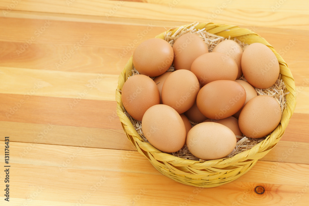 Chicken eggs in a wicker straw on wooden background Chicken eggs in a wicker straw on wooden background
