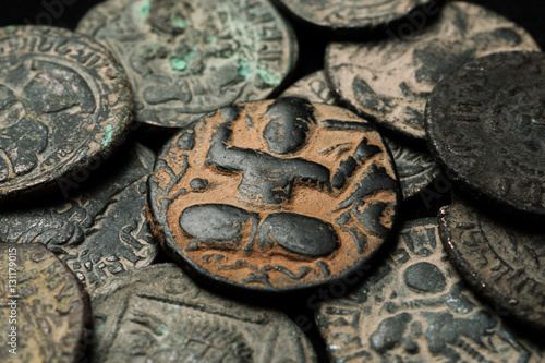 Obraz na płótnie Ancient islamic copper coin in pile of other coins w salonie