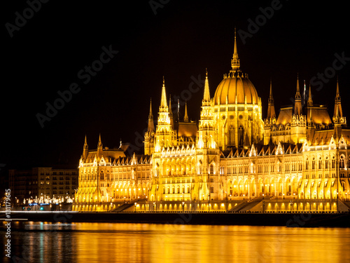 Night view of illuminated historical building of Hungarian Parliament, aka Orszaghaz, with typical symmetrical architecture and central dome on Danube River embankment in Budapest, Hungary, Europe. It