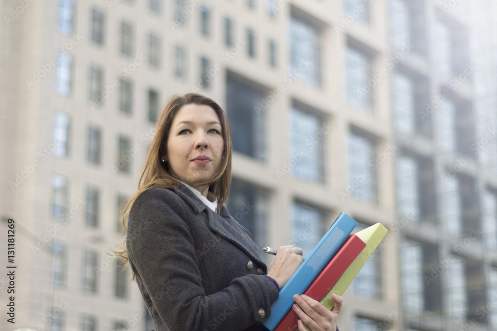 Young businesswoman with notebook in front of office building. Young businesswoman with notebook in front of office building.