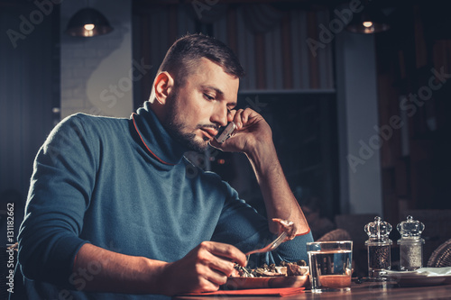 Handsome man eating and speaking on mobile phone at the restaurant