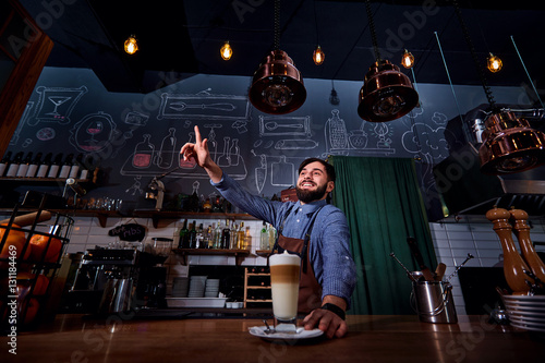 Barman barista uniform making coffee tea cocktails in the bar,smiles raised his finger up restaurant, shop.