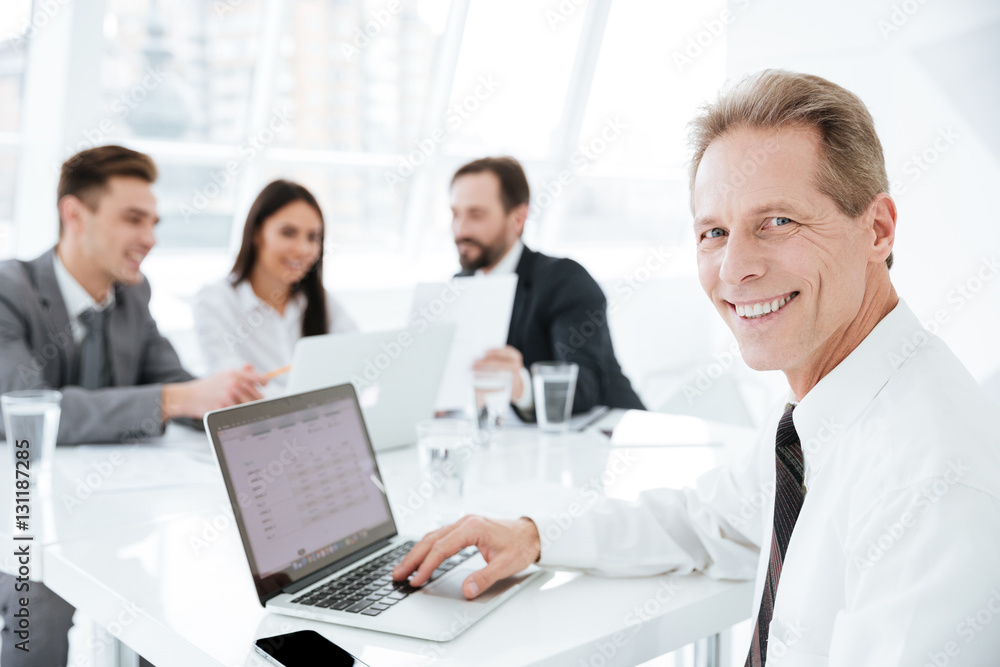 Elderly business man by the table with colleagues Elderly business man by the table with colleagues