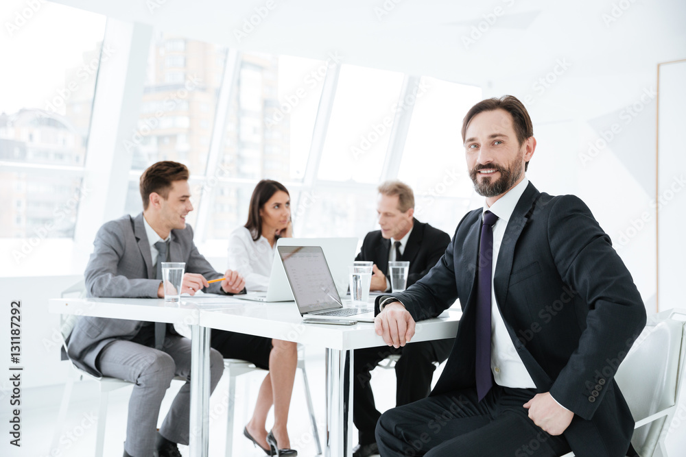 Confident Elderly business man by the table with partners Confident Elderly business man by the table with partners