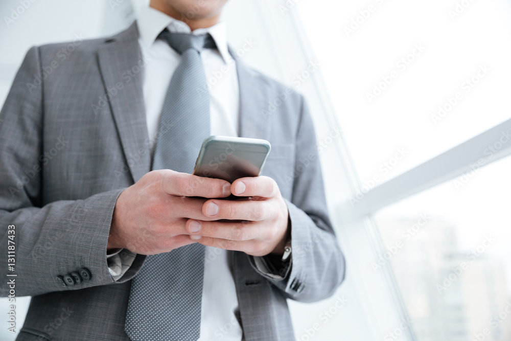 Cropped image of business man using phone near the window Cropped image of business man using phone near the window