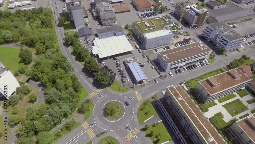 We can see a roundabout close to a big indoor parking lot and there is also a town next to it. Wide-angle aerial shot.
We can see a roundabout close to a big indoor parking lot and there is also a town next to it. Wide-angle aerial shot.