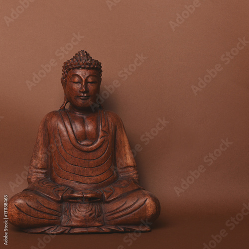 Wooden buddha statue against brown backgound