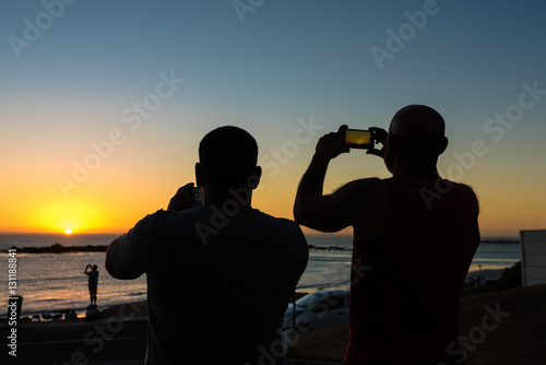 People taking photos of a sundown with their smartphones