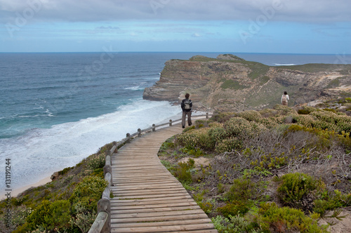 Tourist  on vacation walking on wooden path and looking at the beautiful view. Cliffs and ocean at Cape of Good Hope, South Africa
