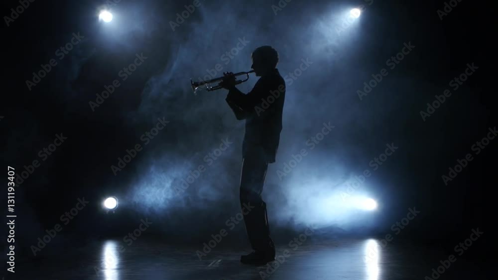 Trumpeter in a smoky studio playing a wind instrument Trumpeter in a smoky studio playing a wind instrument