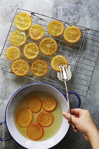 Female hand placing a slice of candied orange on a grill to dry.