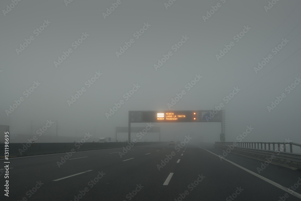 Traveling on the highway with the fog, the sign says: fog along the way, prudence!