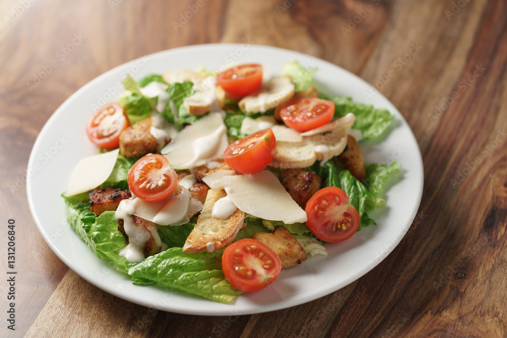caesar salad with cherry tomatoes on wooden table caesar salad with cherry tomatoes on wooden table