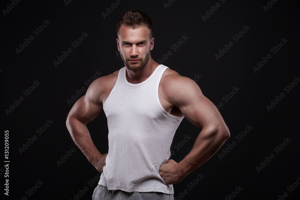 Studio portrait of athletic young man wearing white undershirt isolated on black background Studio portrait of athletic young man wearing white undershirt isolated on black background