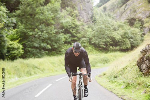 A young road cyclist dressed in black, attacking the climb in Ch