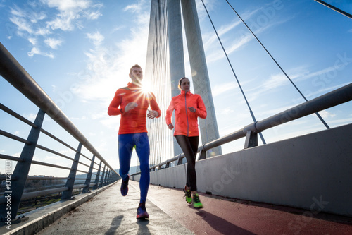 Couple running in a urban environment with sun flare  between them