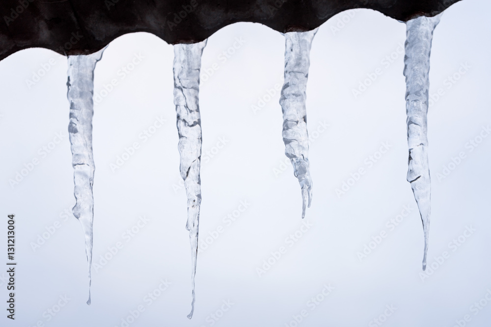 Icicles drooped from schist roof on sky background