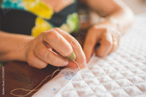 Cropped view of woman sewing hem on quilt photo