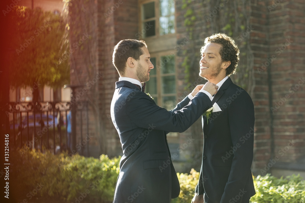 Newlywed gay man adjusting bow tie of partner Newlywed gay man adjusting bow tie of partner