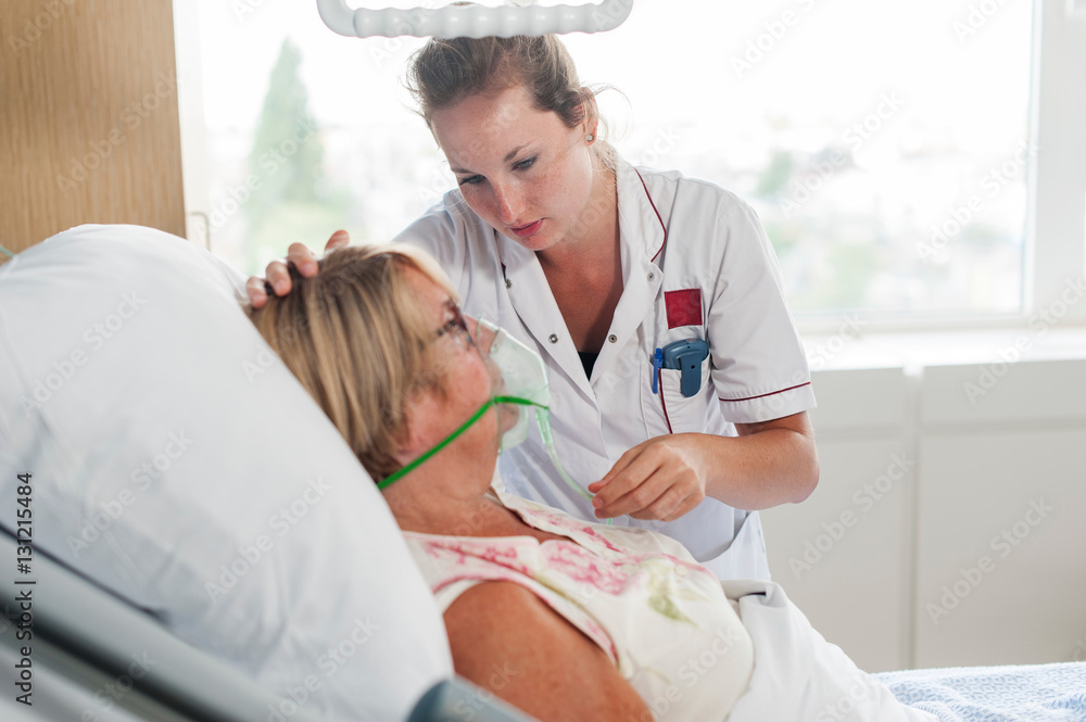 Nurse tending to patient in hospital bed wearing oxygen mask Stock ...