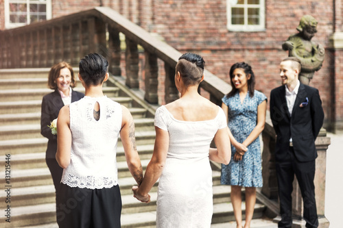 Rear view of lesbian couple standing in front of female priest