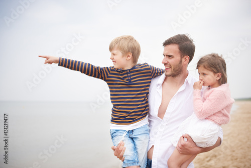 Father carrying children in arms on beach photo