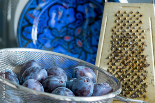 Plums in sieve and grater photo