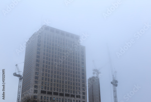 Southbank place tower block with construction cranes in fog, Lon