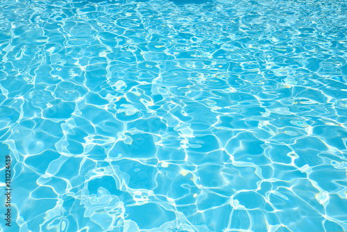 Blue water surface with sun reflection in swimming pool