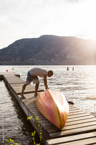 Man turning over boat on pier, Penticton, Canada