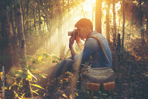 Young Man traveler with retro photo camera walking in forest Fas