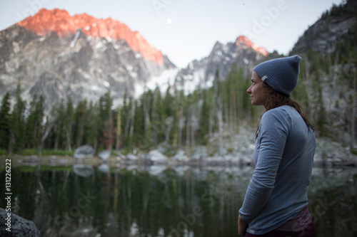 Young woman standing beside lake, looking at view, The Enchantments, Alpine Lakes Wilderness, Washington, USA
