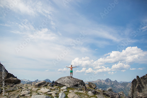 Young woman standing on rock, arms open, The Enchantments, Alpine Lakes Wilderness, Washington, USA