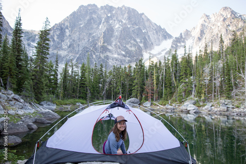 Young woman sitting in tent beside lake, The Enchantments, Alpine Lakes Wilderness, Washington, USA