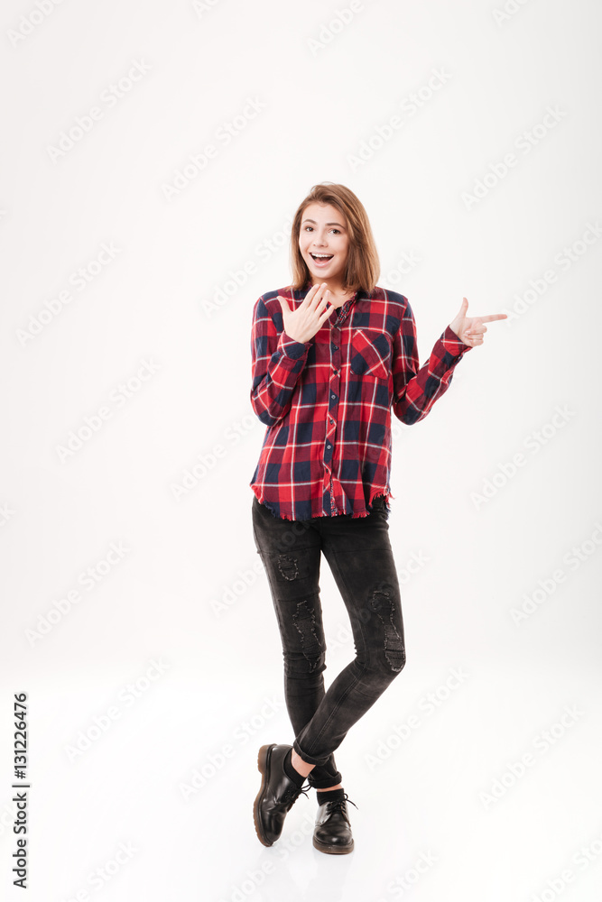 Surprised attractive young woman with opened mouth pointing finger away Surprised attractive young woman with opened mouth pointing finger away