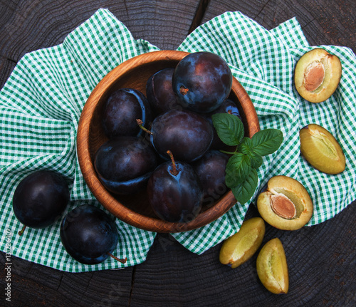 Bowl with plums with green leaves