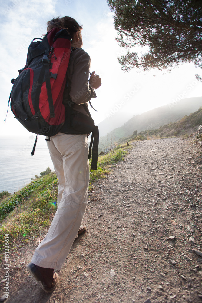femme de dos qui marche sur un sentier du littoral avec un sac